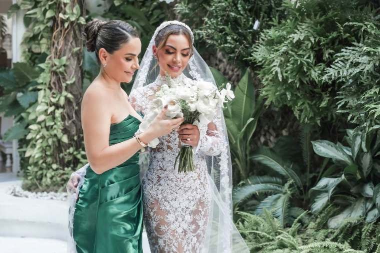 Liliana Céspedes acompañando a la novia con su ramo entre los jardines tropicales de la hacienda, boda en Villavicencio