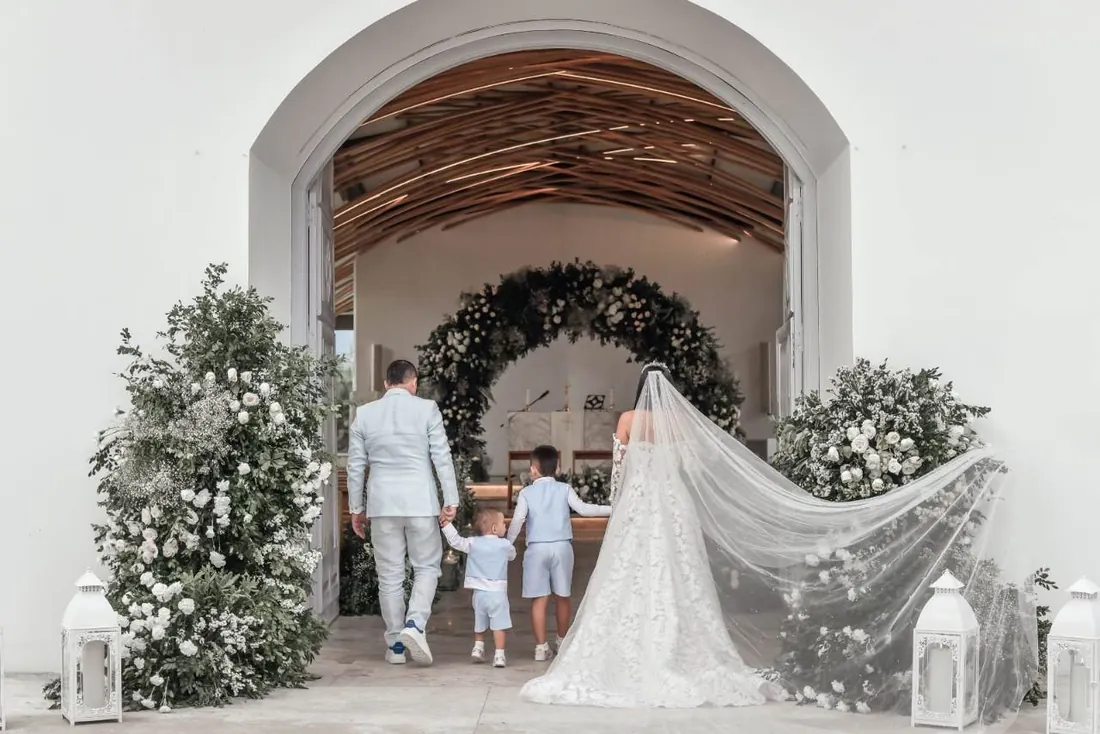 Novia y familia entrando a la capilla de Hacienda Las Marías bajo un arco de flores, boda en Villavicencio