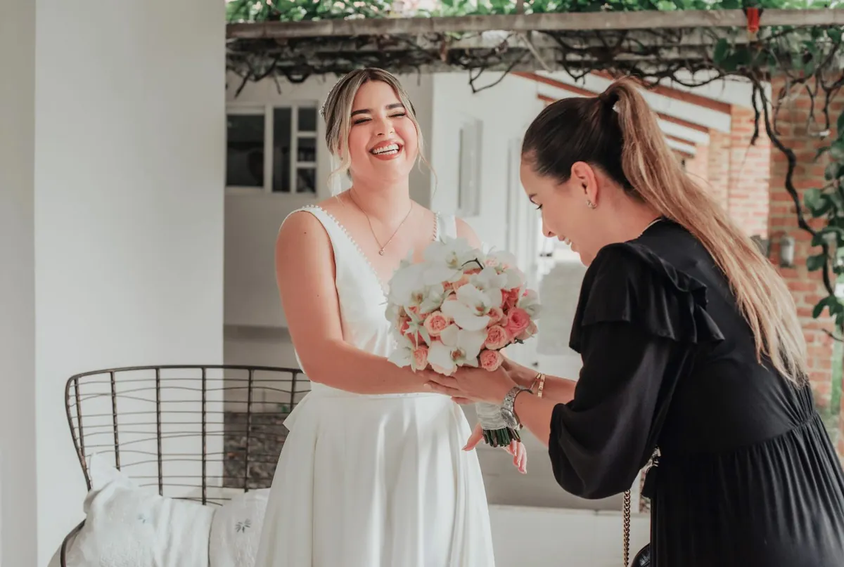 Liliana Céspedes, wedding planner en Villavicencio, entregando el ramo a una novia sonriente el día de su boda